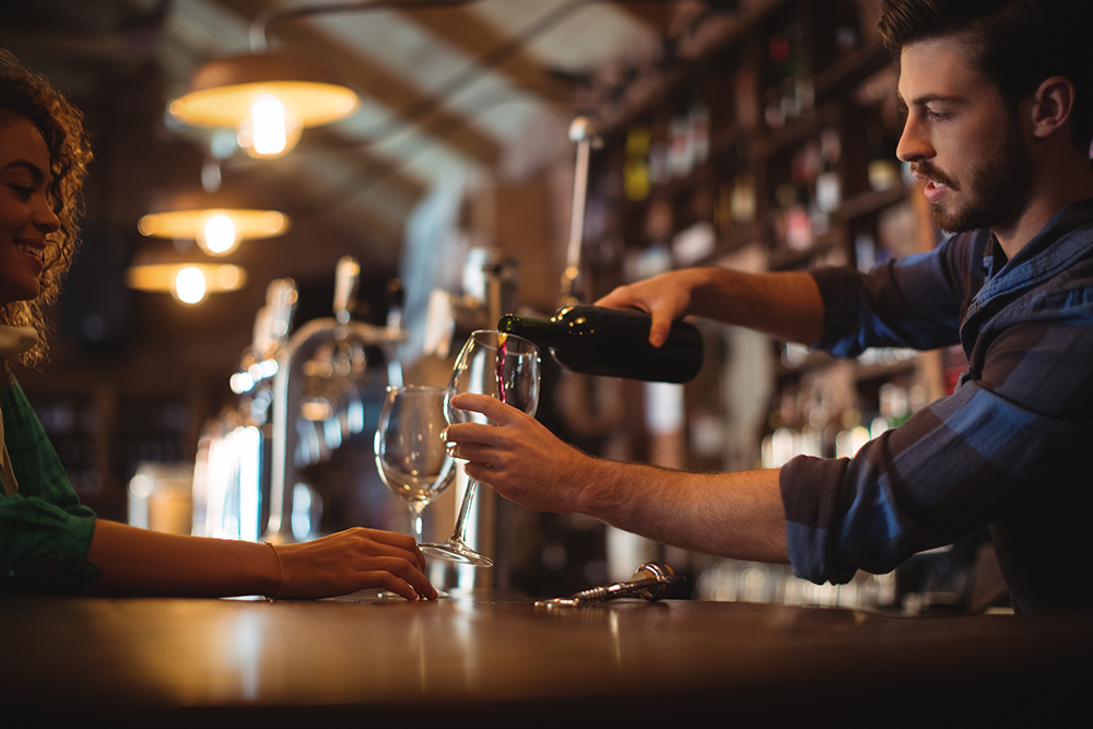 Male bar tender pouring wine in glasses illuminazione bancone bar